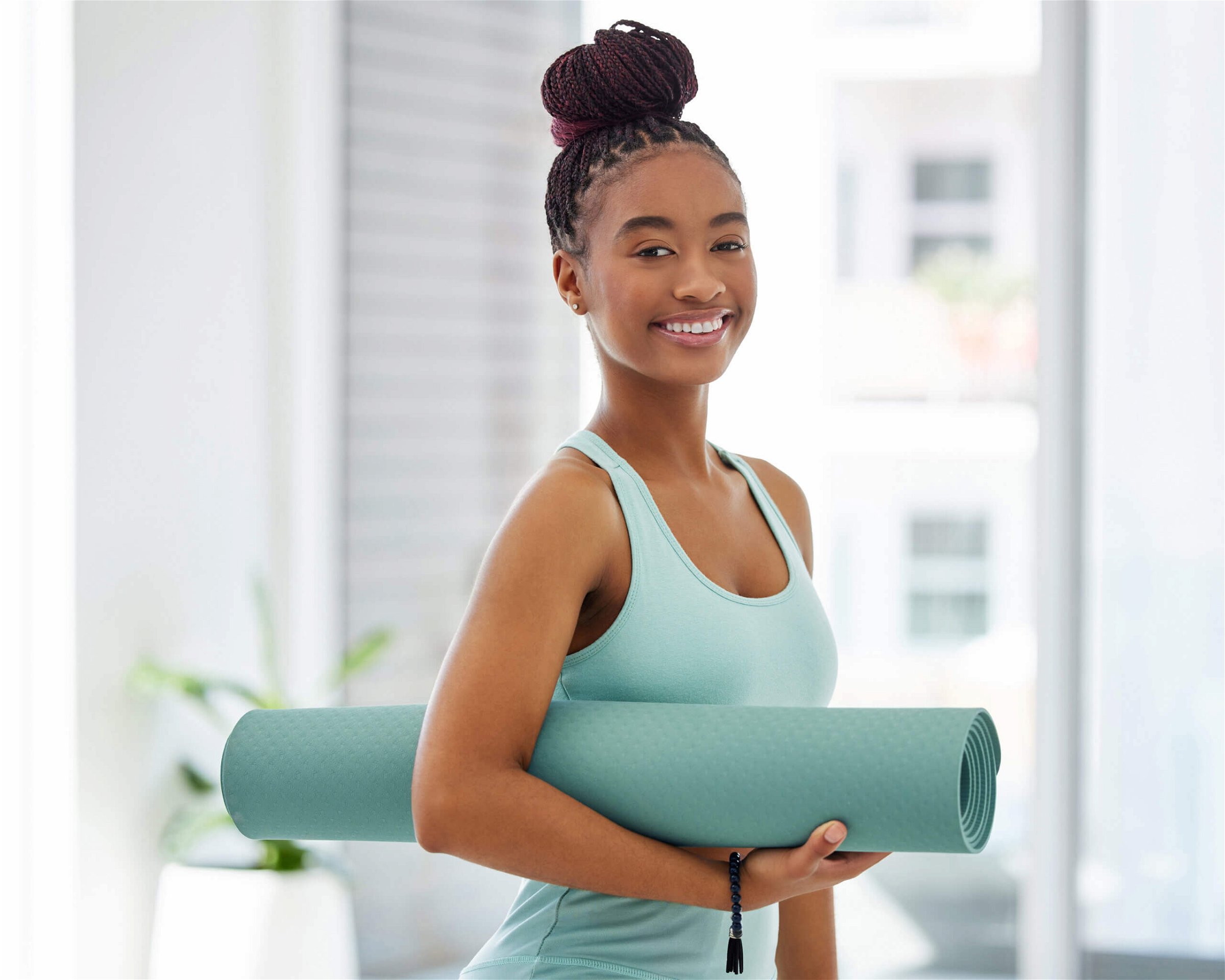 Shot of an attractive young woman standing alone and holding a yoga mat in a studio.
